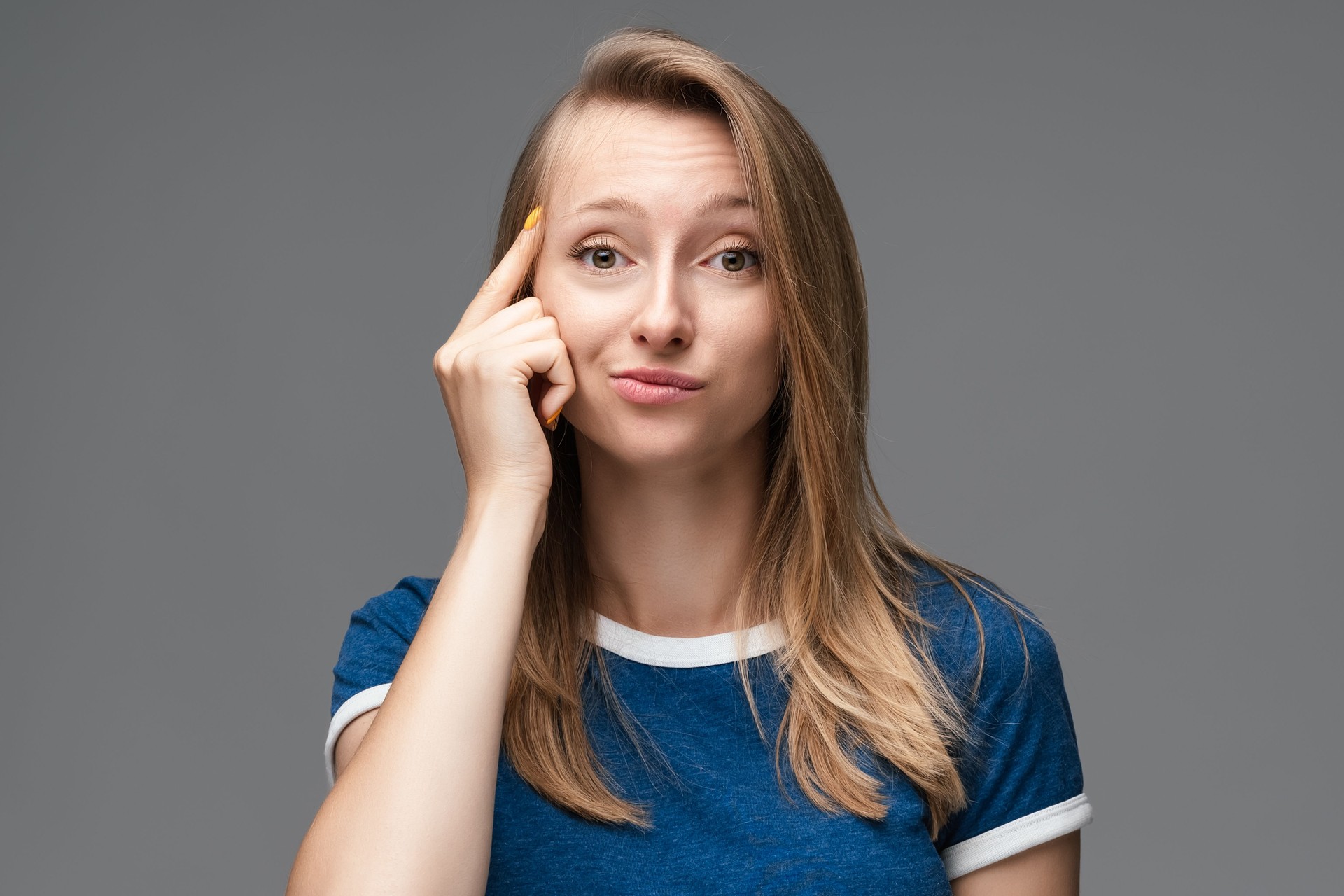Studio shot of Confident young female pointing with finger at head. Concept of thinking. Be smart and think